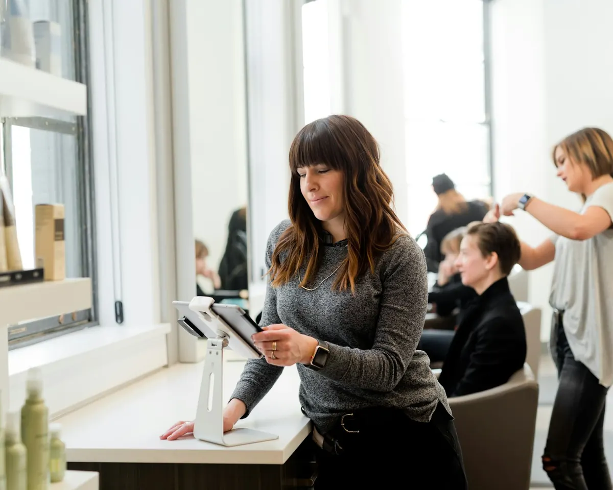 A stylist checking the salon calendar on a tablet between clients