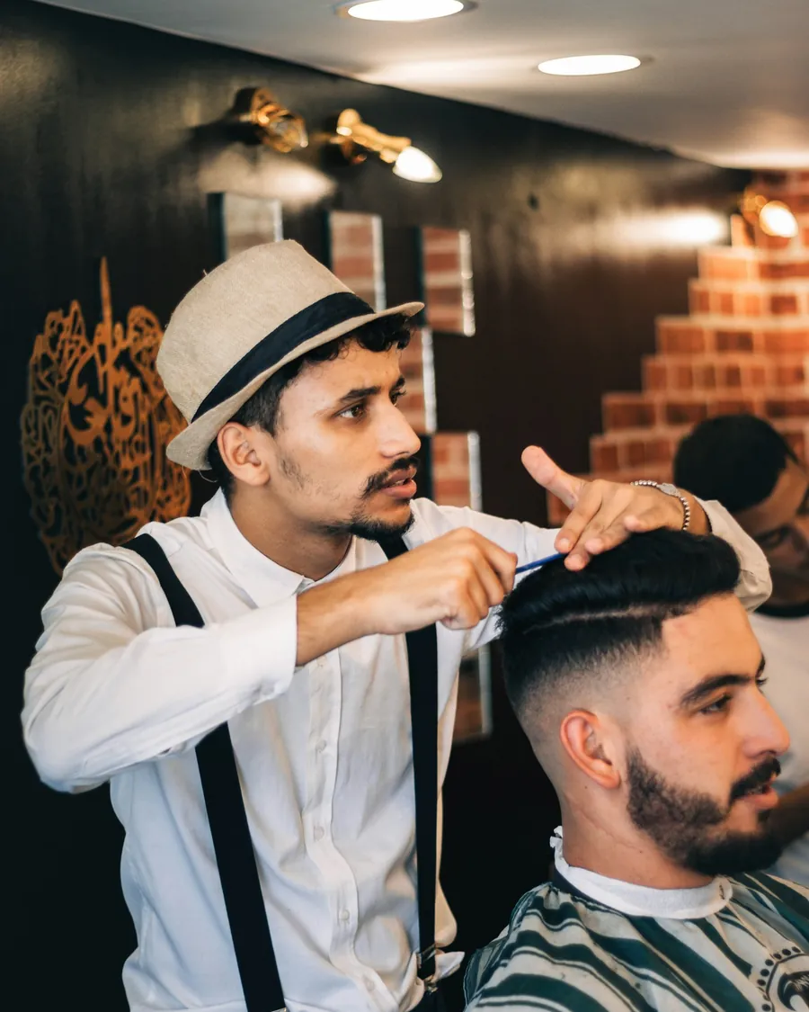 A barber finishing a customer's haircut